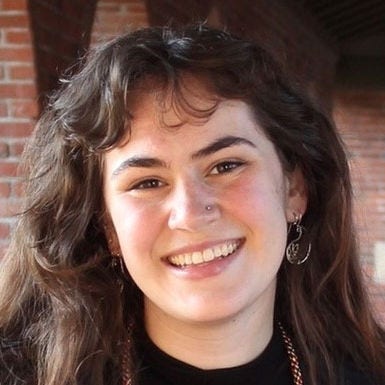 Headshot of Clarissa Troutman, BS, long brown hair, black jacket with red trim.