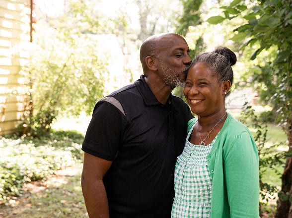 Man kisses woman on forehead; they smile warmly.