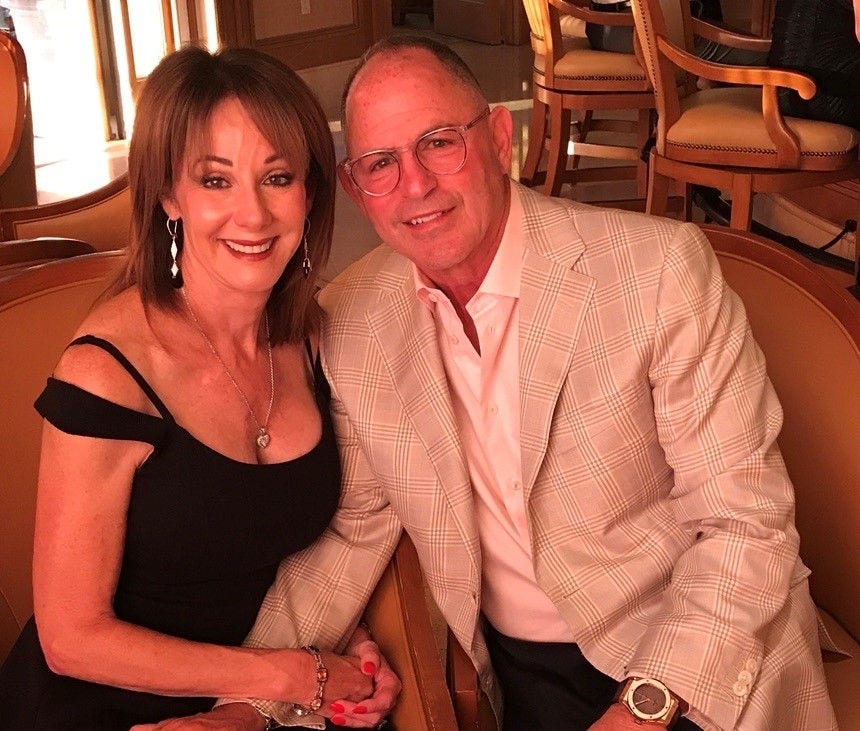 Smiling couple dressed elegantly, seated together indoors
